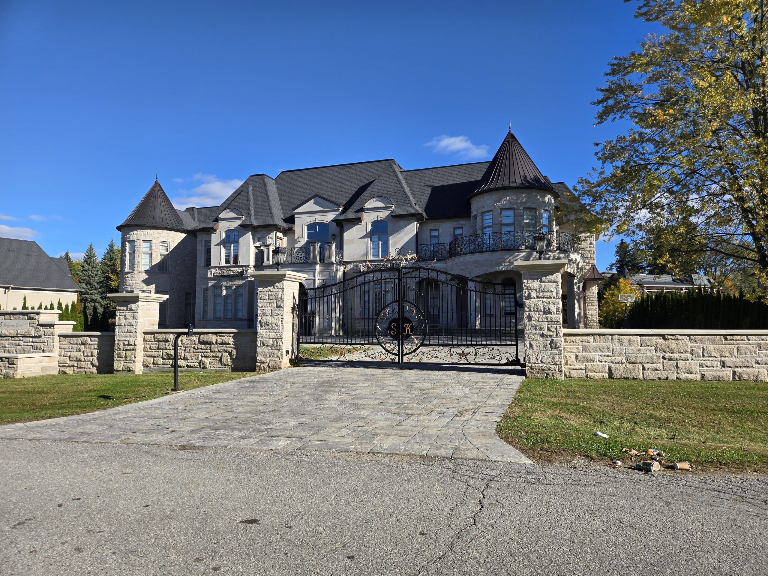 Stone château-style home with corner turrets and a gated driveway