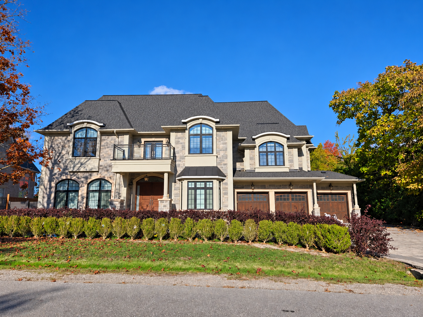 Two-storey stone home with arched windows and a three-car garage